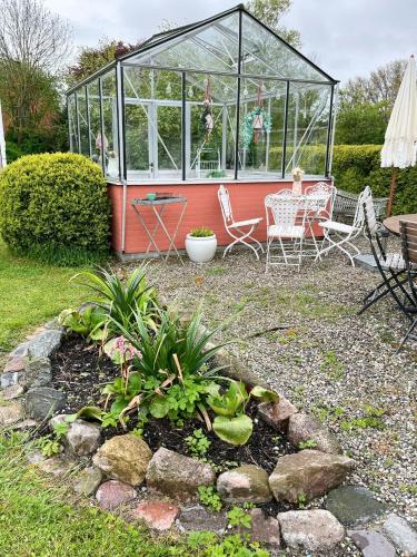 a garden with a greenhouse and chairs and plants at Idyllic Countryside Home Close To Baltic Sea in Nykøbing Falster