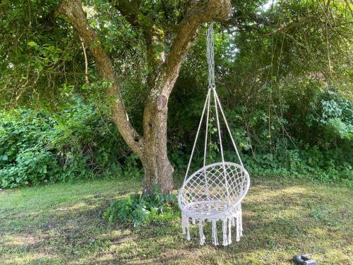 a white swinging chair in front of a tree at Idyllic Countryside Home Close To Baltic Sea in Nykøbing Falster