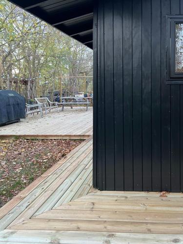 a black building with a wooden floor next to a patio at Birdsong And The Sound Of Waves At Reersø in Gørlev