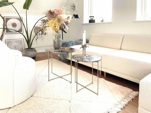 a living room with a white couch and two tables at Idyllic House With Cliff Formations And Ocean View in Sandvig
