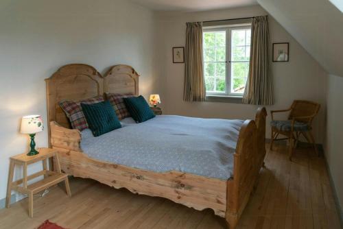 a bedroom with a large wooden bed and a window at Historic House In Skjoldungernes Land Park in Kirke Såby