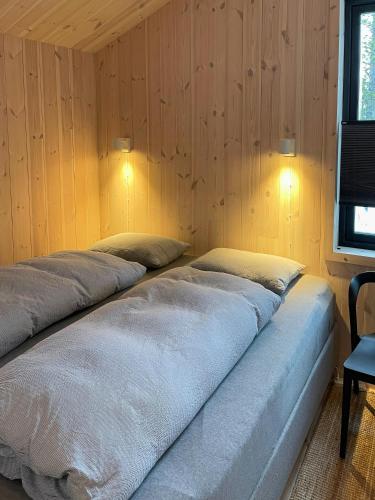 two beds in a room with wooden walls and a television at Cozy Cabin At The Gateway To Jotunheimen in Vaga