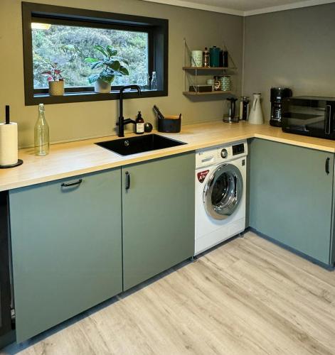 a kitchen with a sink and a washing machine at Charming Seaside Cabin With Amazing View in Hardbakke