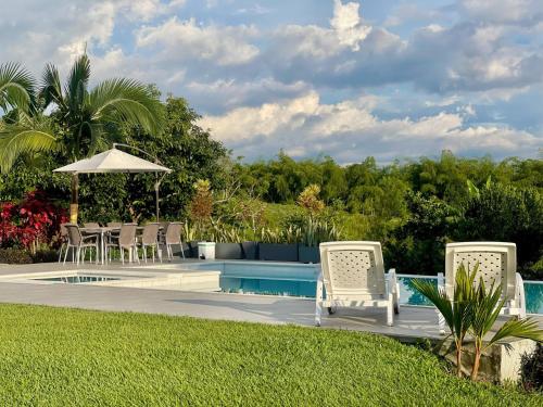 a pool with chairs and a table and an umbrella at Torcaza Casa de Campo in Quimbaya