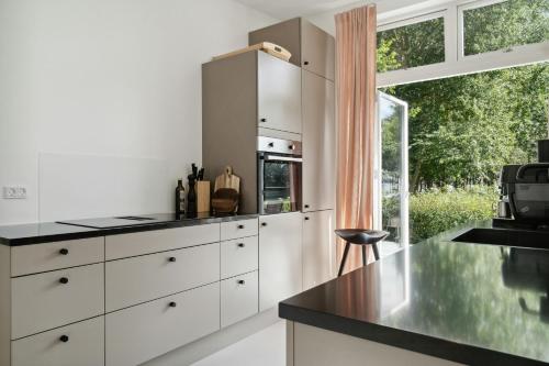 a kitchen with white cabinets and a large window at Moderne Familiesommerhus Ved Hav Og Aktiviteter in Nysted