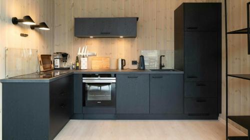 a kitchen with blue cabinets and a stove top oven at Near-Sea Boat House With Panoramic Views in Sykkylven