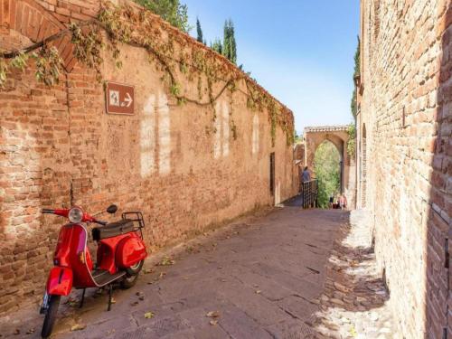 a red scooter parked next to a brick building at Hideaway Near San Gimignano in Bagnolo