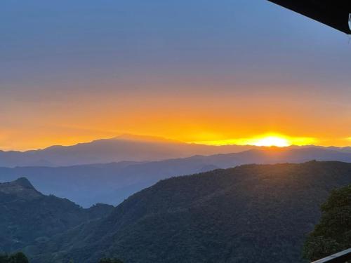 a sunset over a mountain range with the sun setting at Kcafe Ancestral Glamping in Venecia
