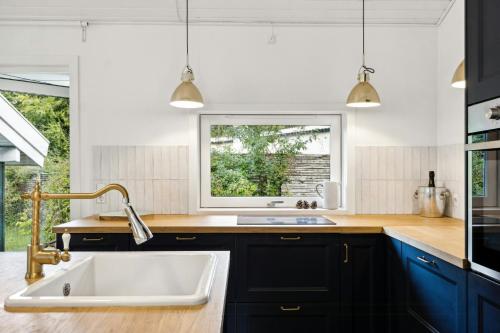 una cocina con fregadero y ventana en Summer House Near Hornbæk Beach, en Hornbæk