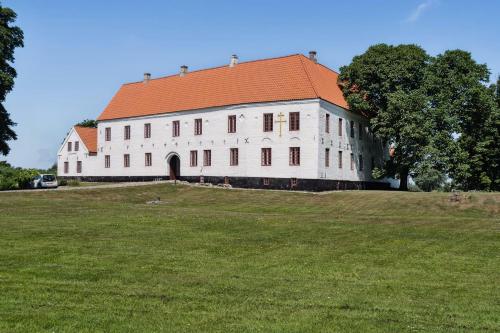 a large white building with an orange roof on a field at Unique Stay At Odden Manor & Museum in Hjørring