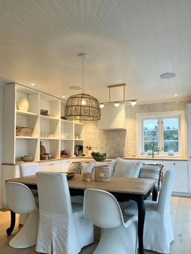 a dining room with a table and white chairs at Modern & Charming Summer House Near Risør in Søndeled