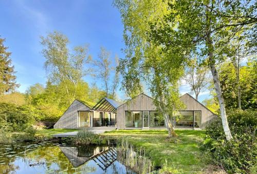 a house in the woods with a pond at Architect-Designed House Close To Hornbæk in Tikøb