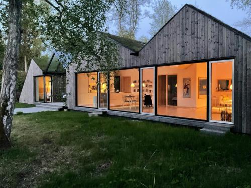 a house with glass walls and a gambrel roof at Architect-Designed House Close To Hornbæk in Tikøb
