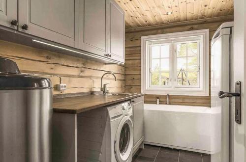 a kitchen with a washing machine and a sink and a tub at Log Cabin Near Historic Senhovd in Veggli