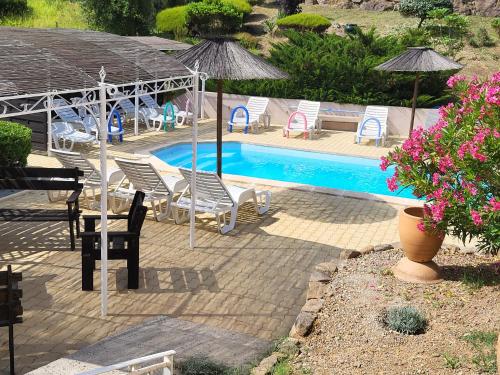 a swimming pool with chairs and umbrellas and a table at 15mn de Cannes, Villa la Soleiade , Gite ,Lodge , type T2, clim, piscine, parking au Lac de Saint-Cassien VAR in Montauroux