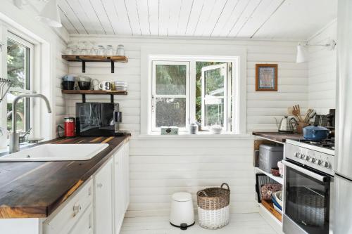 een keuken met witte muren en houten aanrechtbladen bij Classic 1937 Cottage On A Natural Plot in Nykøbing Sjælland