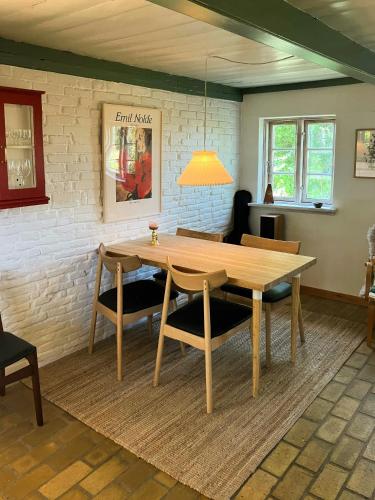 a dining room with a wooden table and chairs at Peaceful Summer House Near Ulvemosehule Forest in Glamsbjerg