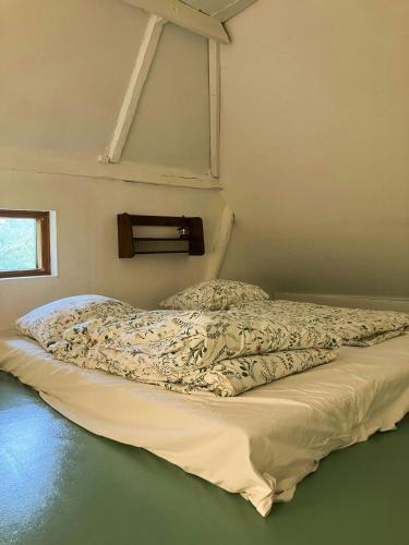 an unmade bed in a room with a window at Peaceful Summer House Near Ulvemosehule Forest in Glamsbjerg