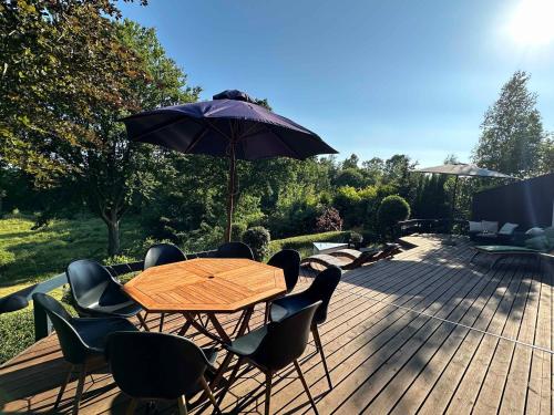 a wooden table with chairs and an umbrella on a deck at Summer House With Terrace Overlooking Nature in Tikøb