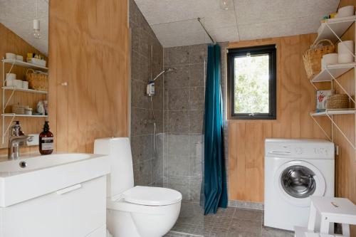 Un baño con inodoro y lavadora. en House In The Woods Near Beach With Peaceful Vibes, en Saeby
