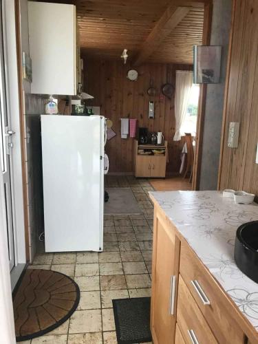 a kitchen with a white refrigerator in a room at Cozy Summer House In Løkken in Løkken