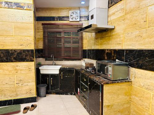 a kitchen with a sink and a microwave at Smart Apartment in Gullberg Lahore in Lahore