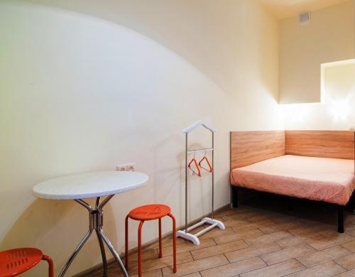 リヴィウにあるMini Apartments on Roppoporta 7a-2のテーブル、スツール2脚、ベッド1台が備わる客室です。