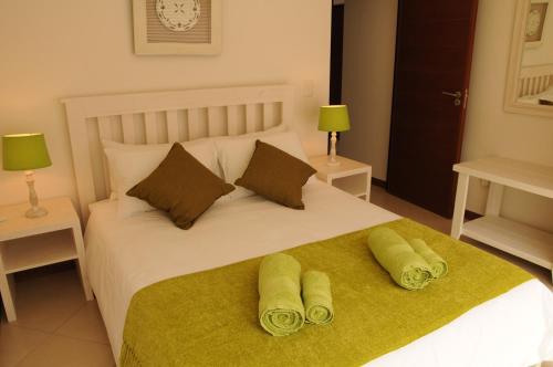Una cama blanca con dos toallas verdes encima. en Moringa Gardens # 03 E, en Swakopmund