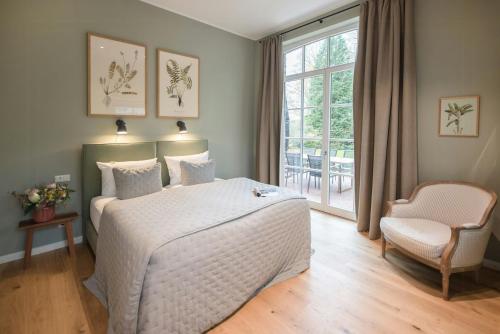a bedroom with a bed and a chair and a window at Getaway In East Frisia Elegant Lakeside Apartment in Friedeburg