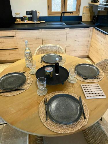 une table en bois avec des assiettes et des verres dans l'établissement Stone Sheepfold With Sea View In Corsica, à Sari-dʼOrcino