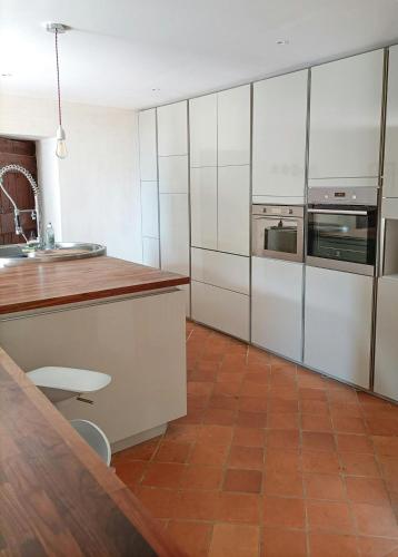 d'une cuisine avec des placards blancs et du carrelage marron au sol. dans l'établissement Family Home In The Heart Of Beaujolais, à Régnié