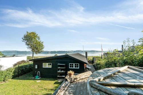 a small house on a deck next to a boat at Family Home With Sauna And Fjord View in Børkop