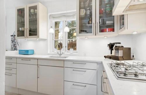 a white kitchen with white cabinets and a sink at Beachfront Summerhouse With Amazing View And Peace in Hesselager