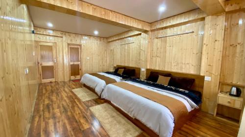a large bed in a room with wooden walls at Keylong villa in Kyelang