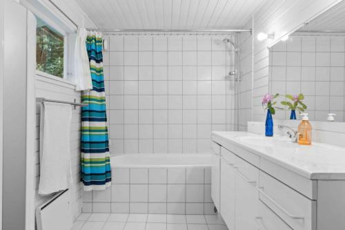ein weiß gefliestes Bad mit einer Dusche und einem Waschbecken in der Unterkunft Cozy Holiday Home Near The Beach And Nature in Frederiksværk
