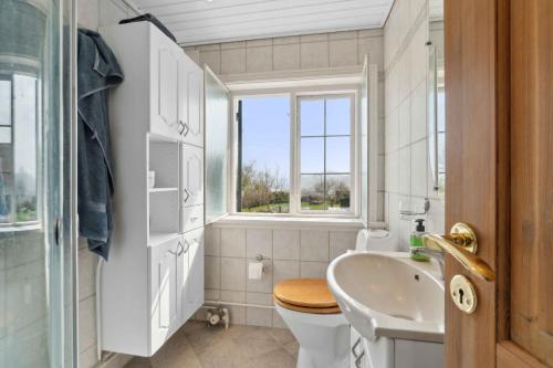 a bathroom with a sink toilet and a window at Holiday Home In Årsdale With Sea View in Svaneke