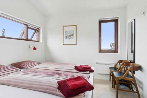 a bedroom with a bed and a chair and two windows at Beautiful Home In As Vig, 100 M From The Beach in Sønderby