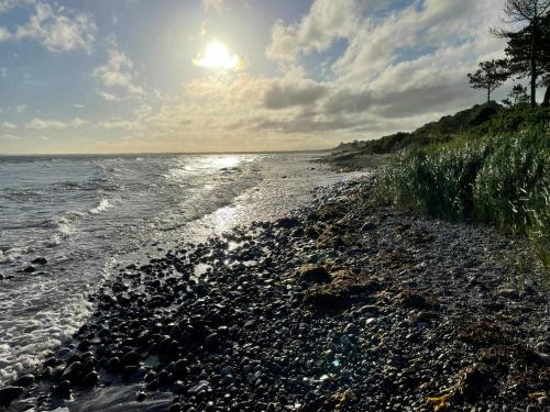 a rocky shoreline with the sun shining on the water at Apartment With Lovely Views In Veddinge Bakker in Fårevejle