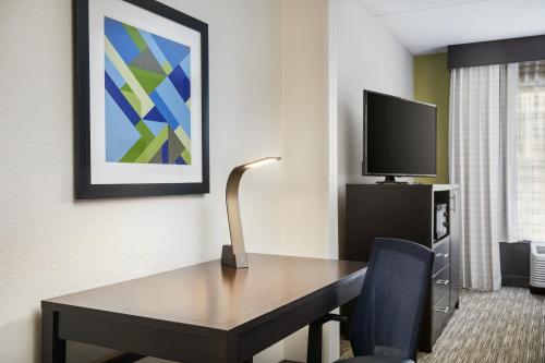 a hotel room with a desk and a tv at Holiday Inn Express & Suites Jacksonville South East - Medical Center Area by IHG in Jacksonville