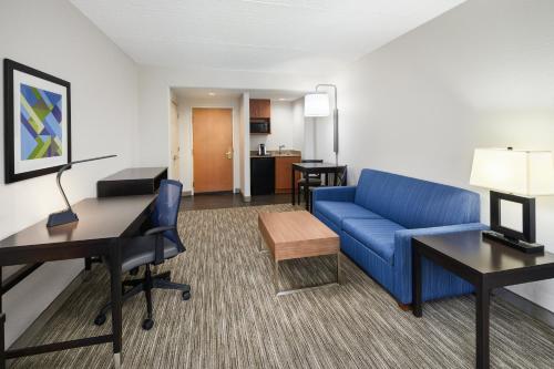 a living room with a blue couch and a desk at Holiday Inn Express & Suites Jacksonville South East - Medical Center Area by IHG in Jacksonville