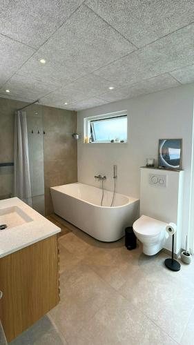 a large bathroom with a tub and a toilet at Modern Holiday Home Near Vesterløkken Beach in Tanderup