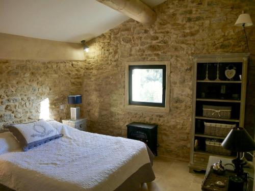 une chambre avec un lit et un mur en pierre dans l'établissement Cozy House In The Heart Of Provence, à La Roque-sur-Pernes