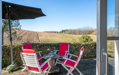three chairs and a table with an umbrella on a patio at Modern House With Sea View In Kårup in Fårevejle