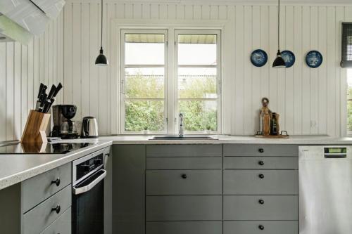 a kitchen with white cabinets and blue plates on the wall at Classic Lovingly Renovated Near Beach in Kirke-Hyllinge