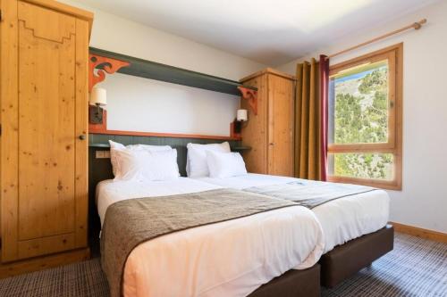 une chambre avec un grand lit et une fenêtre dans l'établissement Résidence Les Arcs 1950 Le Village - maeva Home - Appartement 3 Pièces 6 Personnes - Prestige MAE-1564, à Bourg-Saint-Maurice