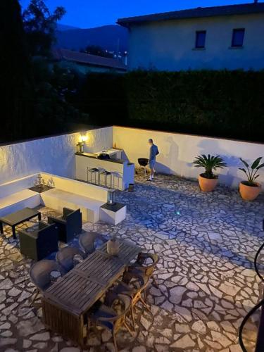 un patio avec une table et des chaises en bois et une personne dans l'établissement French Idyll In Authentic Village, à Villelongue-dels-Monts