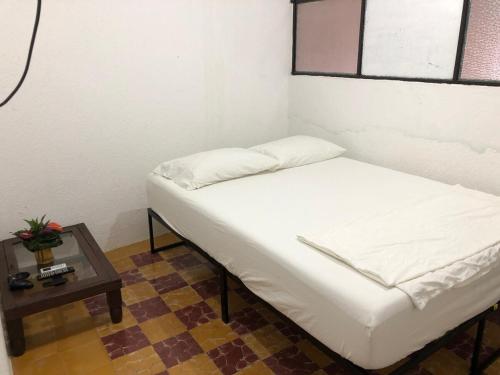 a small bed in a room with a table at Cuarto Telera- amplio, céntrico- Casa de Teru in Tapachula
