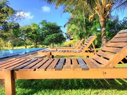 a row of wooden benches sitting next to a pool at Nature World Jungle Paradise in Udawalawe