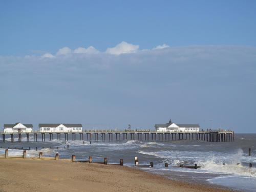 a view of a beach with a pier in the water at Butler's Barn in Darsham