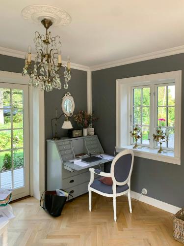 an office with a desk and a chair and a chandelier at New England Inspired Holiday Home In Rågeleje in Vejby